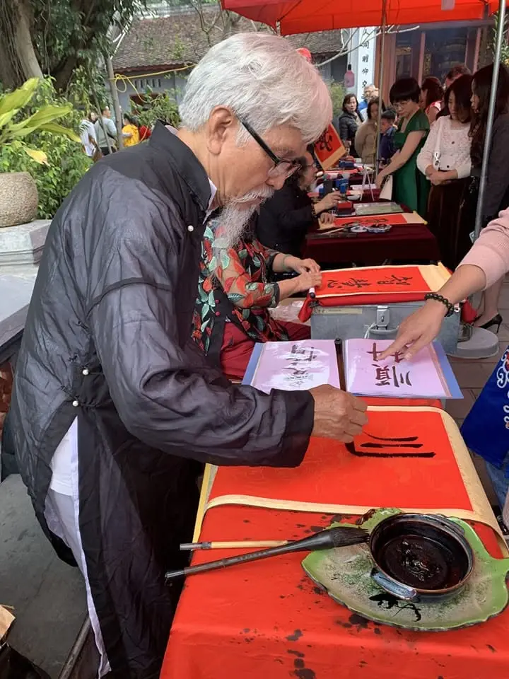 Vietnamese calligraphy artist writing lucky characters during a Tet festival in Vietnam.