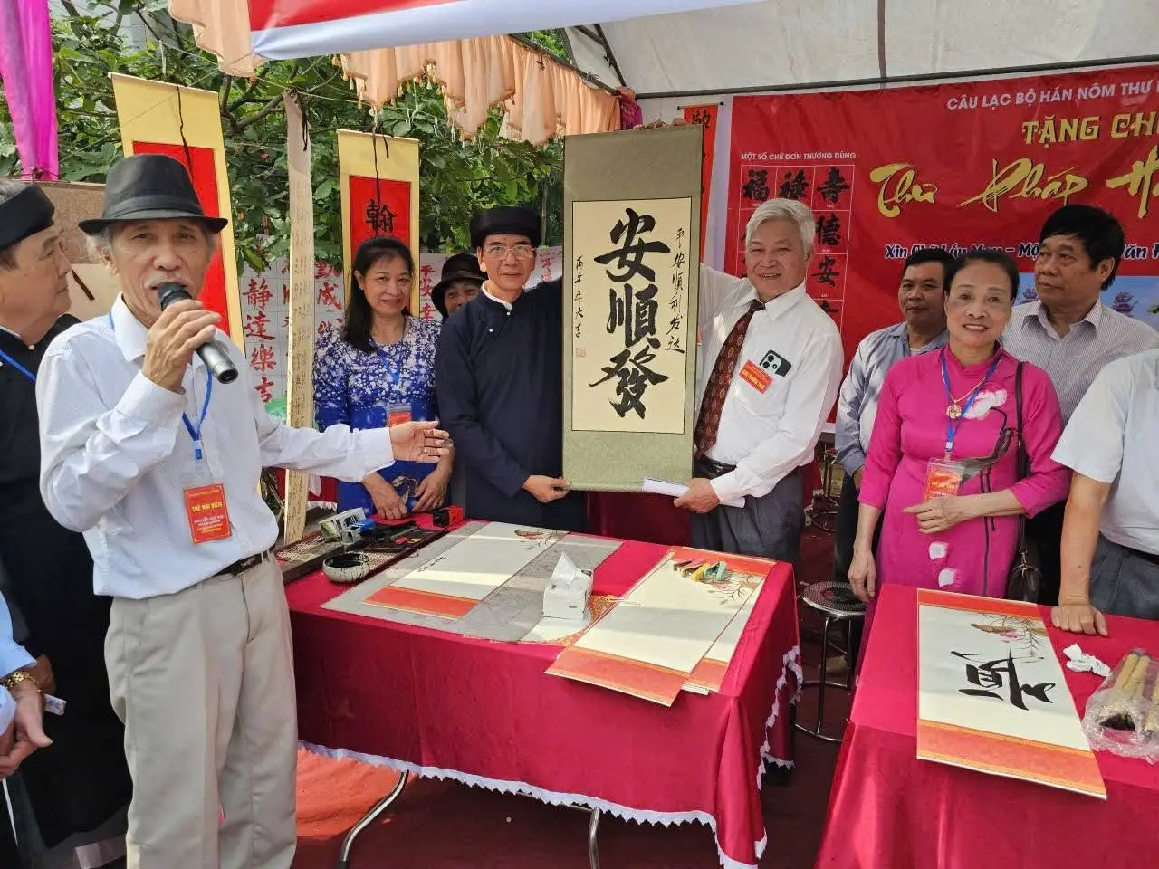 Vietnamese calligraphy artist participating in a cultural event with visitors in Vietnam.